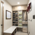 mudroom storage area with bench. The storage is full with shoes and baskets for easy access. This storage area is brown cabinetry with drawers and locker space.