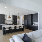 black kitchen with white countertops and brass accents throughout. Stainless steel appliances.