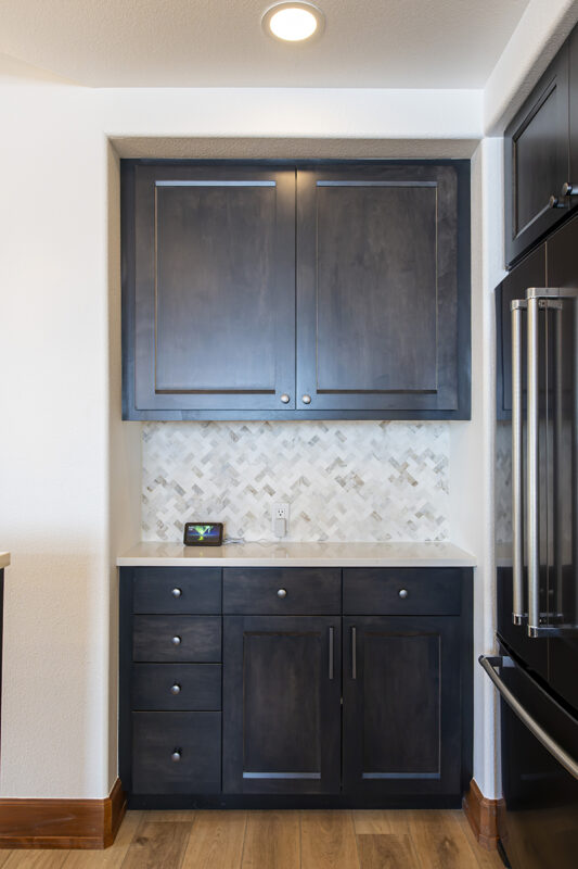 Another view of the black cabinets and the light grey herringbone backsplash.