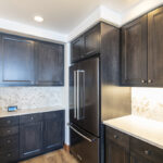 The corner of the kitchen contains a large double door fridge that has a pull-out freezer at the base of it. This offers another view of the floor to ceiling cabinets that cap the end of the kitchen.