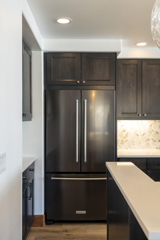 The large double door fridge with cabinets between the top of the fridge & the ceiling.
