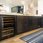 Looking at the cabinets that make up the island. There is a wine cooler on the left hand side, a combination of 3 doors and 5 drawers make up the middle of the island with the dishwasher being on the right end.