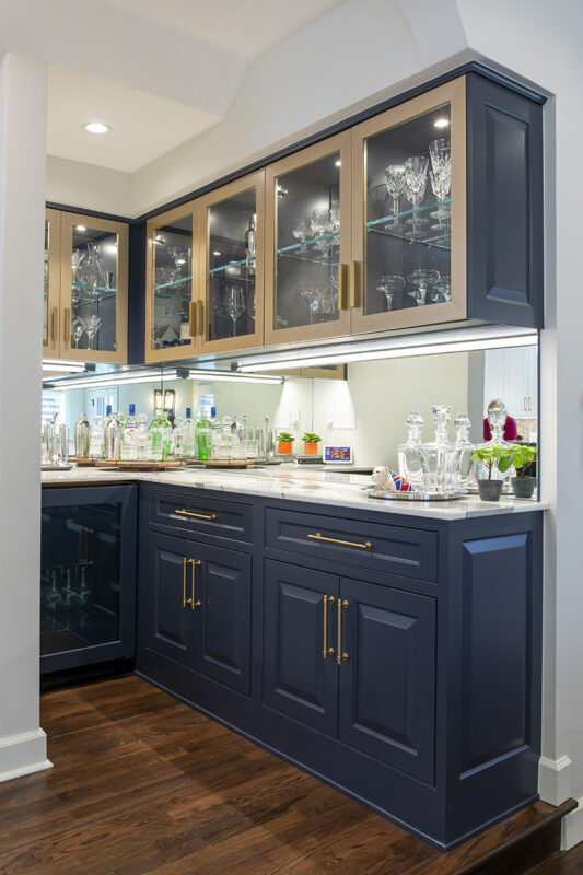 home bar with black cabinetry and gold accents, holding glassware for drinks.