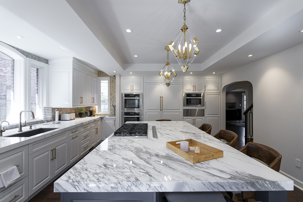 white kitchen cabinetry and vanity, with brass accents. Brown wood floorplan and chair combo.