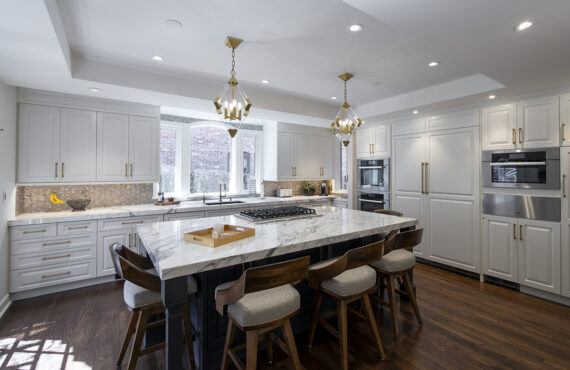 white cabinet kitchen with gold accents and warm wooden floors and chairs
