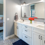 bathroom with white vanity and large rectangular mirror that opens to bedroom