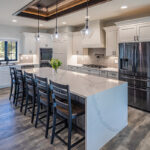 Modern kitchen with white cabinets and granite white countertops. The fixtures are dark grey and their stainless steel appliances. The backsplash of the kitchen is a light grey subway tile.