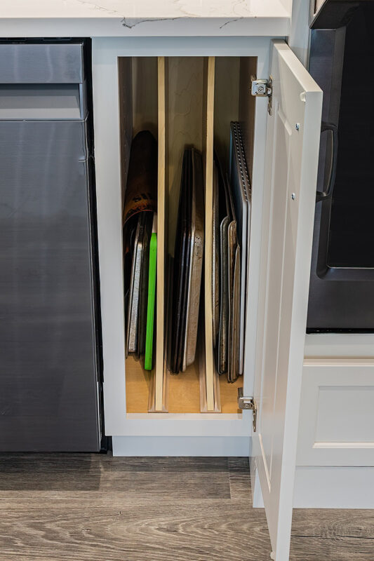 white cutting board cabinet filled with various trays and cutting boards.