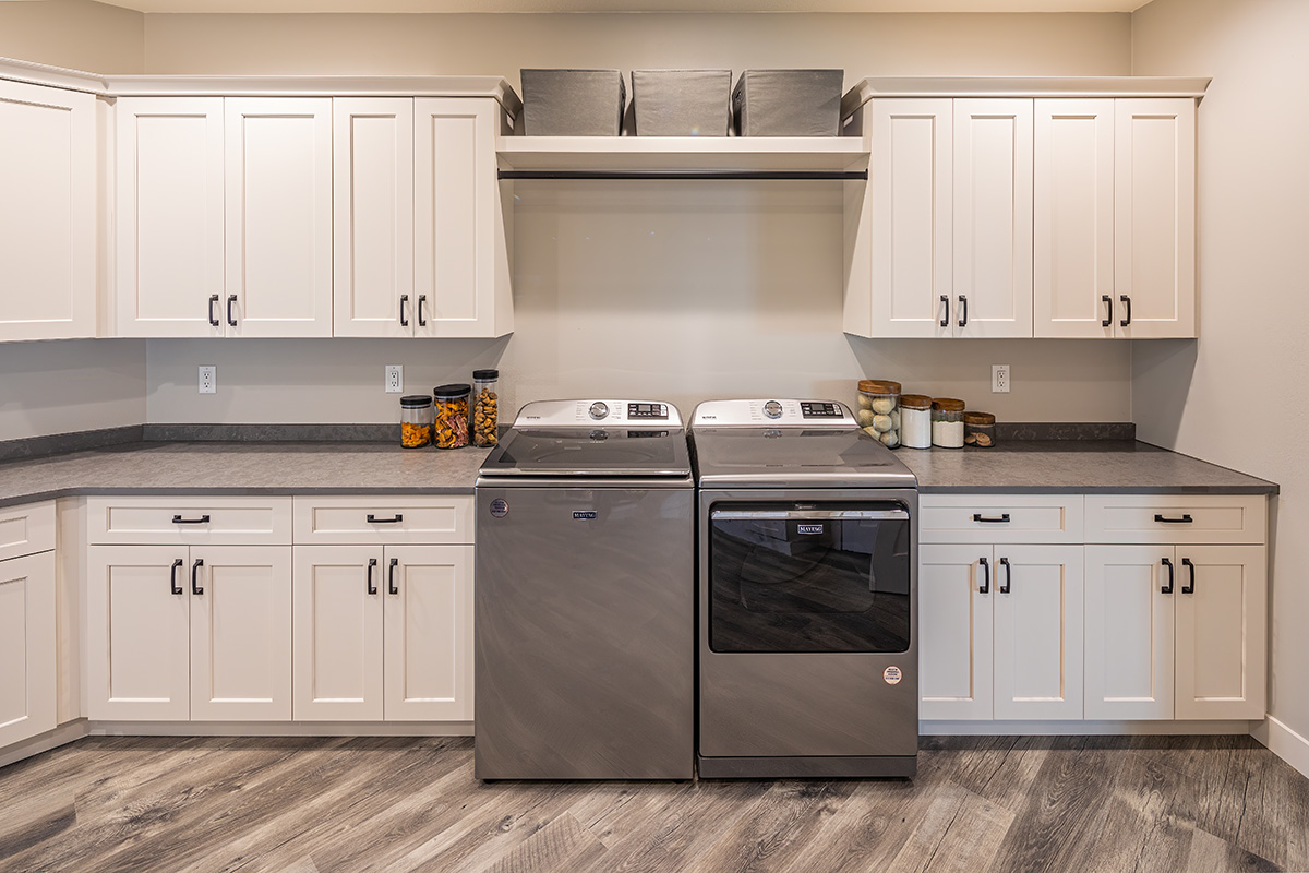 laundry room with white cabinets surrounding a washer & dryer pair