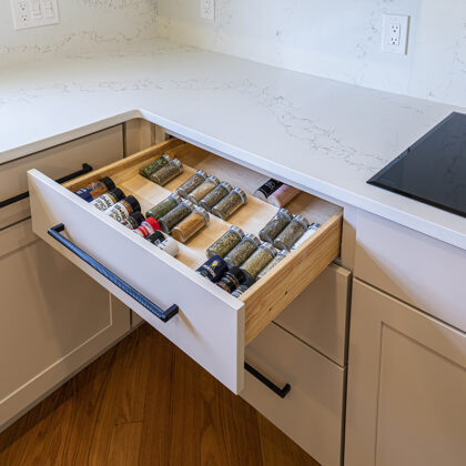 A spice drawer in a kitchen next to the stove top.