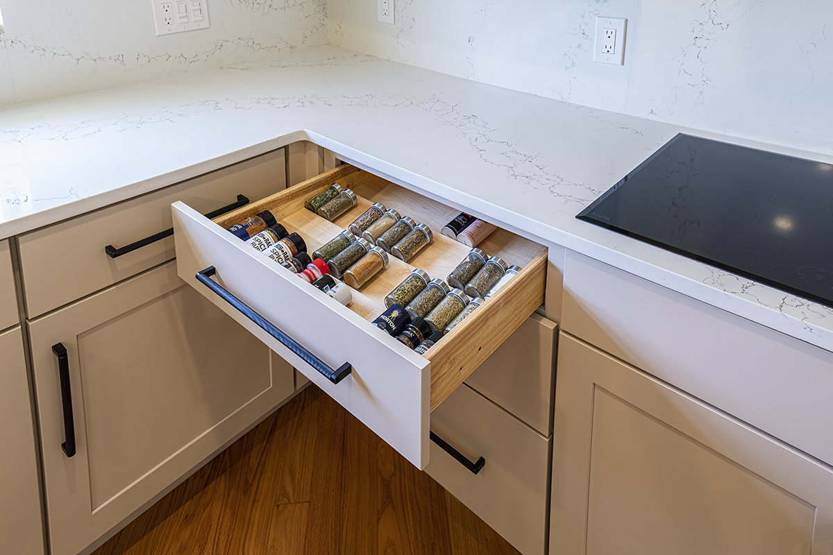 A spice drawer in a kitchen next to the stove top.