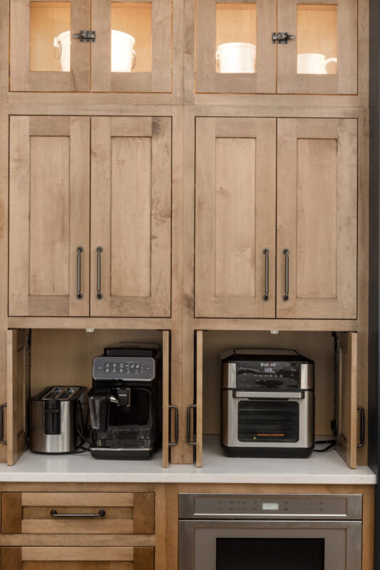 Stained kitchen cabinets with open pocket doors revealing appliances