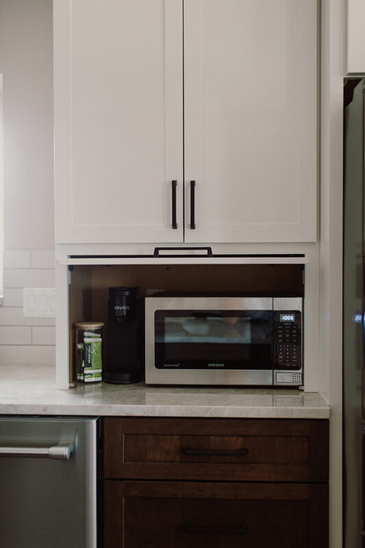 White kitchen appliance storage cabinet with microwave inside.