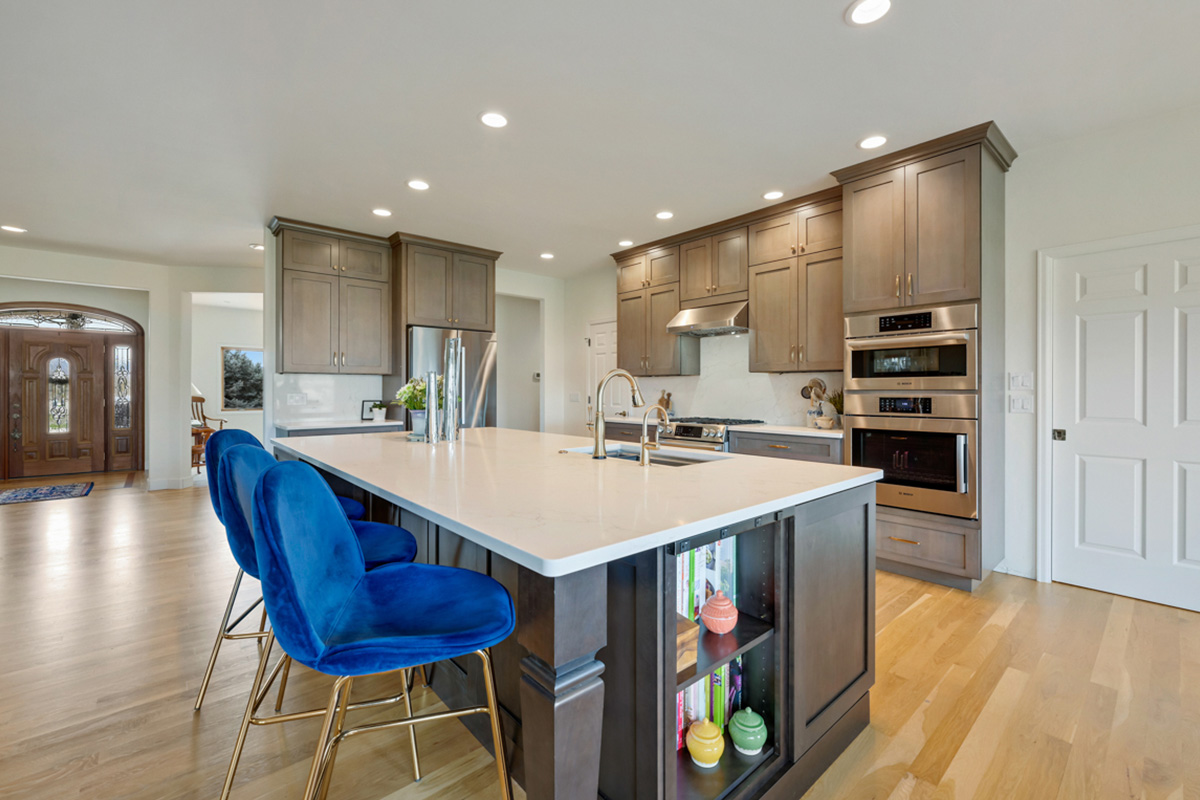 Stained kitchen and island cabinets with blue island chairs