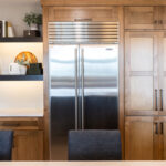 Large side by side fridge enclosed by stained end panels with a walk in pantry door to the right.