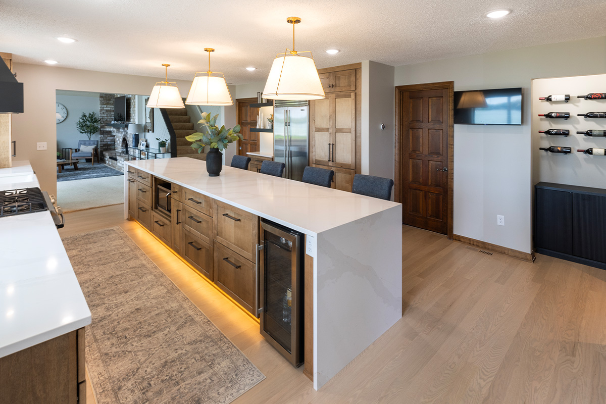 Long kitchen island with tv and fridge beyond