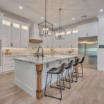 White kitchen with stained accent posts on island and apron on hood.