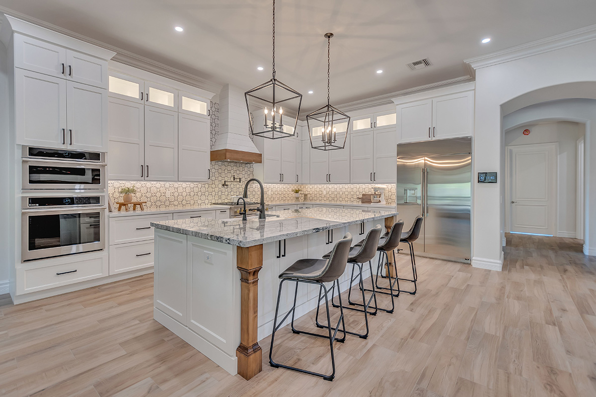 White kitchen with stained accent posts on island and apron on hood.