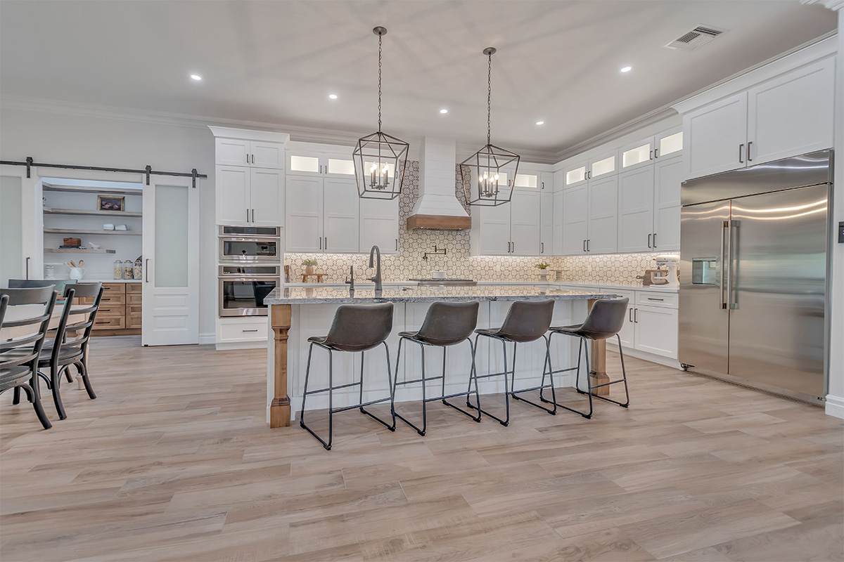 White kitchen with stained accent posts on island and apron on hood.