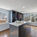 Painted walk-in closet cabinets with hanging closes and a center island for additional storage