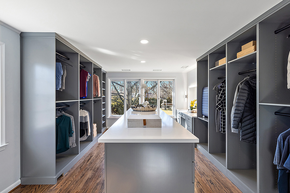 Painted walk-in closet cabinets with hanging closes and a center island for additional storage