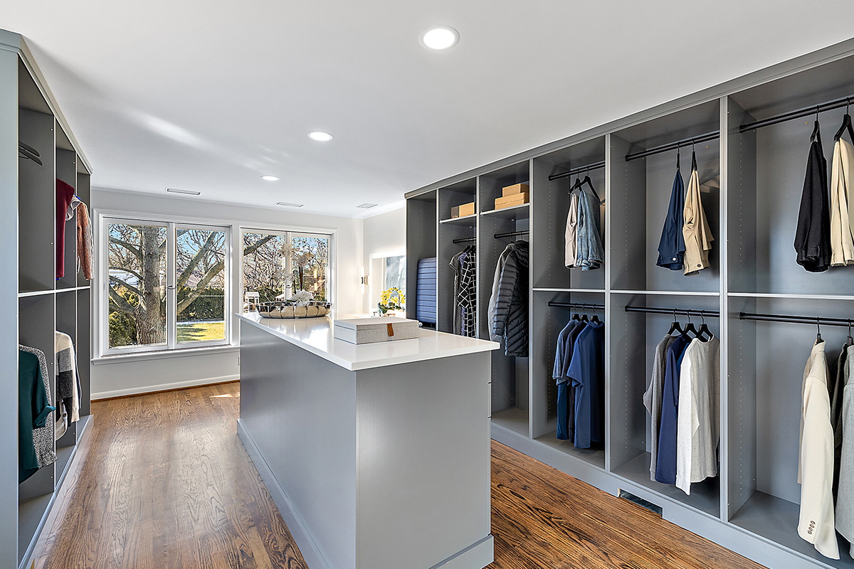 Painted walk-in closet cabinets with hanging closes and a center island for additional storage