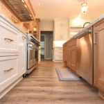 view of kitchen looking from a low point with painted perimeter cabinets to the left and stained island to the right