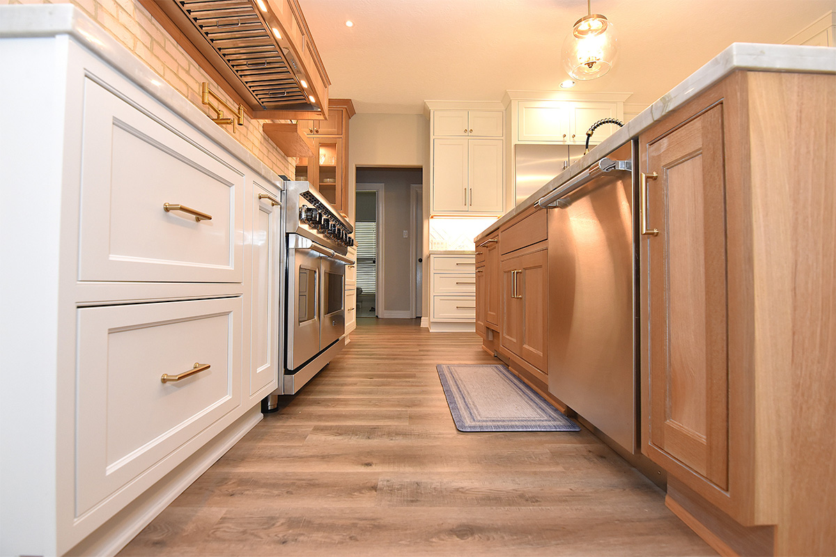 view of kitchen looking from a low point with painted perimeter cabinets to the left and stained island to the right