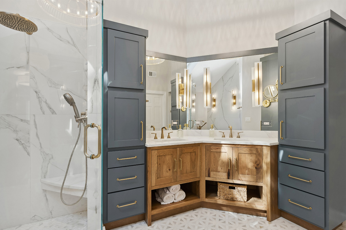 Master bathroom with stained vanity cabinets and painted tall linen cabinets. Also includes a shower with glass walls.