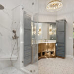 Master bathroom with stained vanity cabinets and painted tall linen cabinets. Also includes a shower with glass walls.