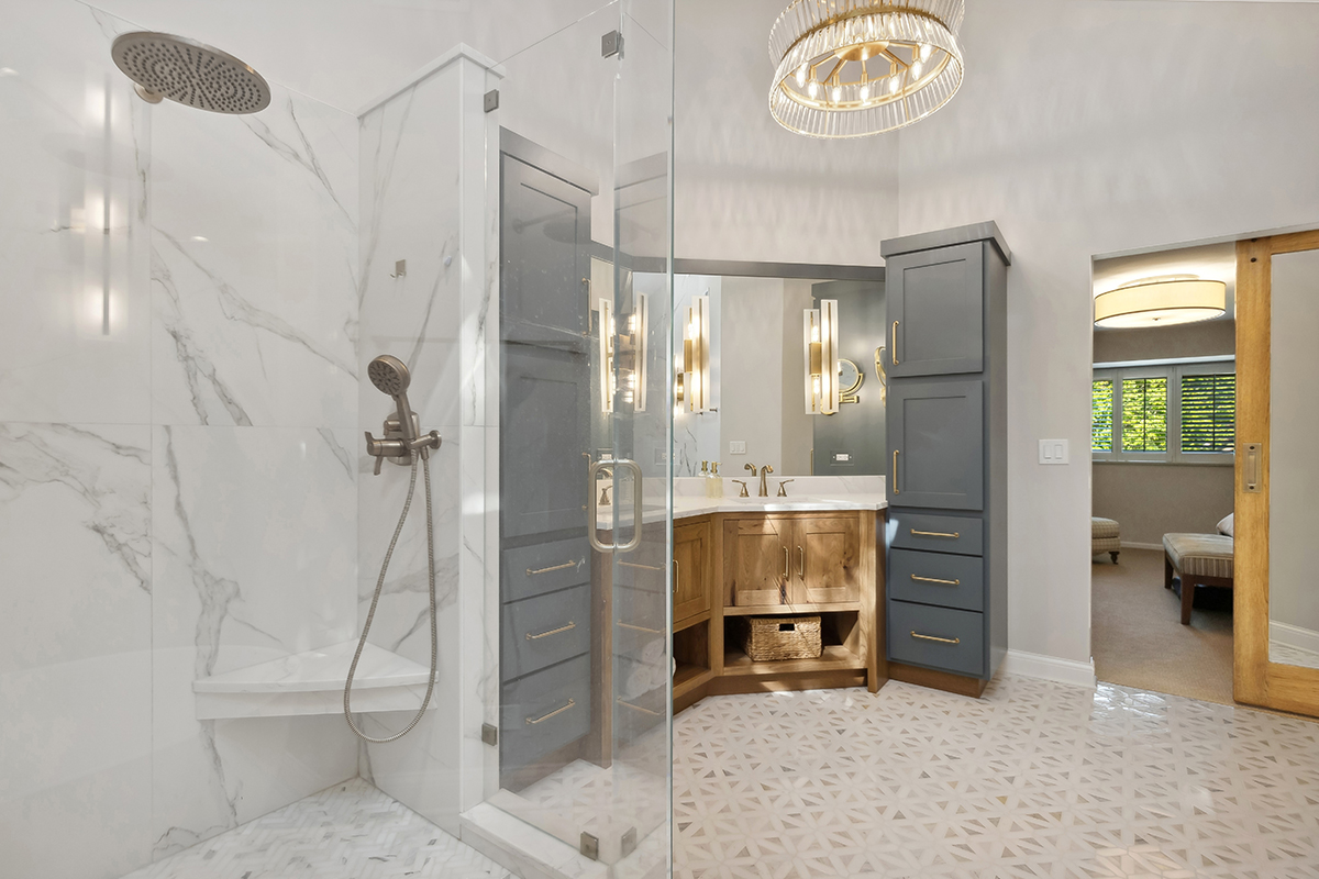 Master bathroom with stained vanity cabinets and painted tall linen cabinets. Also includes a shower with glass walls.