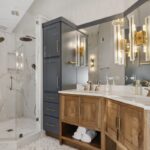 Master bathroom with stained vanity cabinets and painted tall linen cabinets. Also includes a shower with glass walls.