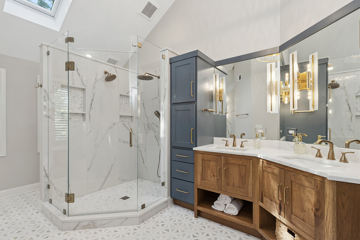 Master bathroom with stained vanity cabinets and painted tall linen cabinets. Also includes a shower with glass walls.