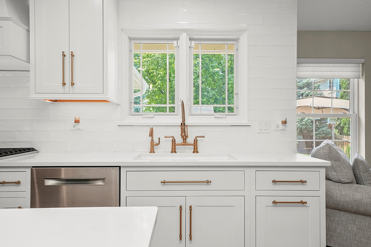 Shows a window above a kitchen sink, surrounded by white painted cabinets