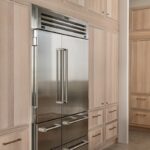 View of stained and painted kitchen cabinets with a large fridge