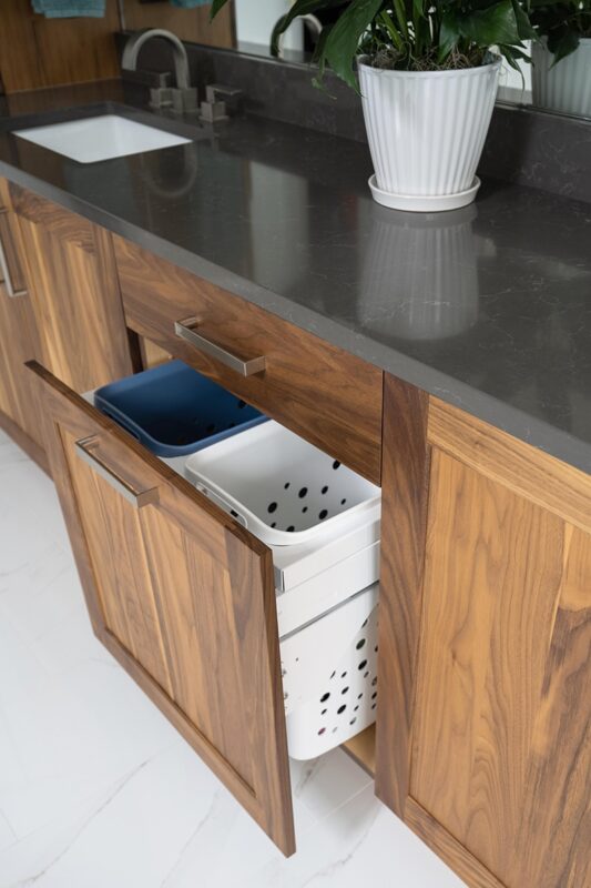 Walnut bathroom cabinets. Showing a hamper pullout.