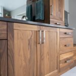 Walnut bathroom cabinets with 2 sinks and countertop storage on each end.