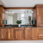 Walnut bathroom cabinets with 2 sinks and countertop storage on each end.