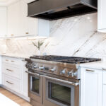 white kitchen cabinets with metal hood and stove