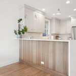 Kitchen peninsula with painted cabinets and a stained wood panel back
