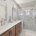 Stained bathroom vanity cabinet with glass wall shower
