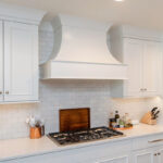White painted kitchen cabinets with curved range hood.