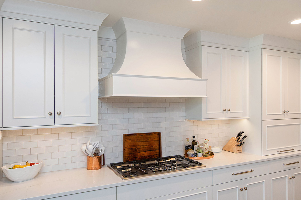 White painted kitchen cabinets with curved range hood.