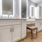 Painted master bath cabinets with backlit mirror and vanity bench