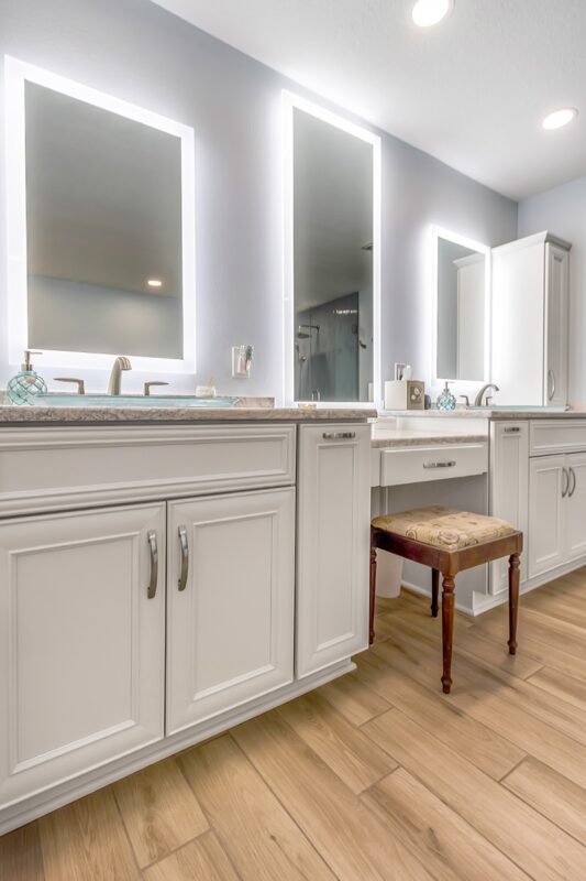 Painted master bath cabinets with backlit mirror and vanity bench