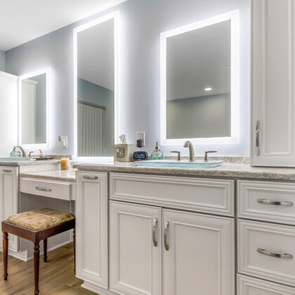 Painted master bath cabinets with backlit mirror and vanity bench