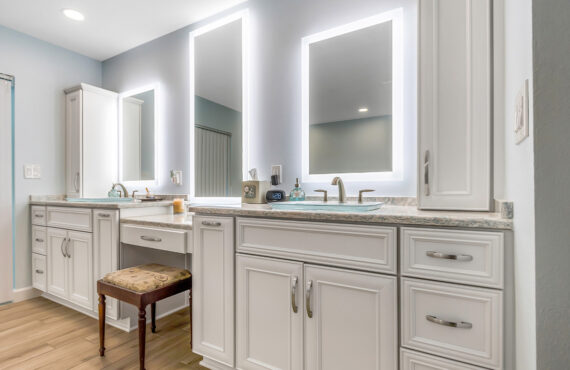 Painted master bath cabinets with backlit mirror and vanity bench