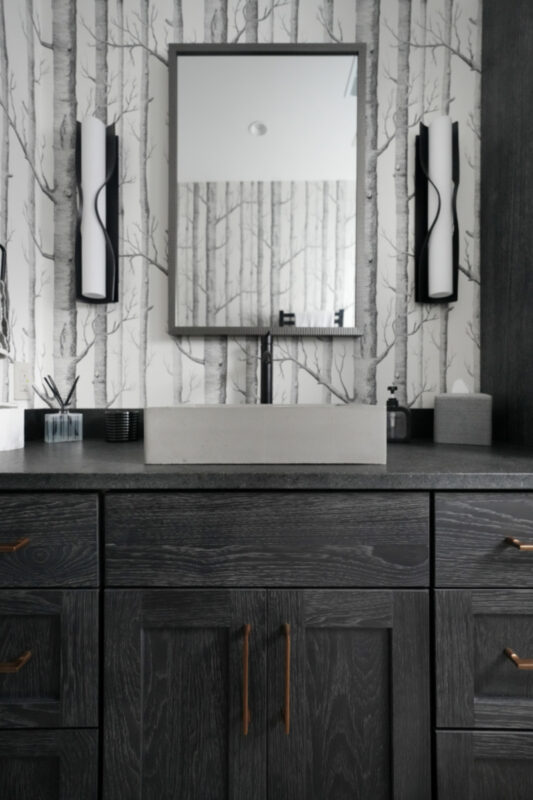 Bathroom vanity cabinets with dark Midnight stain. Bathroom uses "Woods" wall paper.