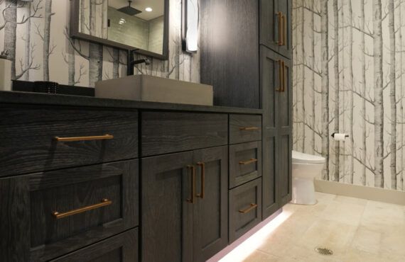 Bathroom vanity cabinets with dark Midnight stain. Bathroom uses "Woods" wall paper.