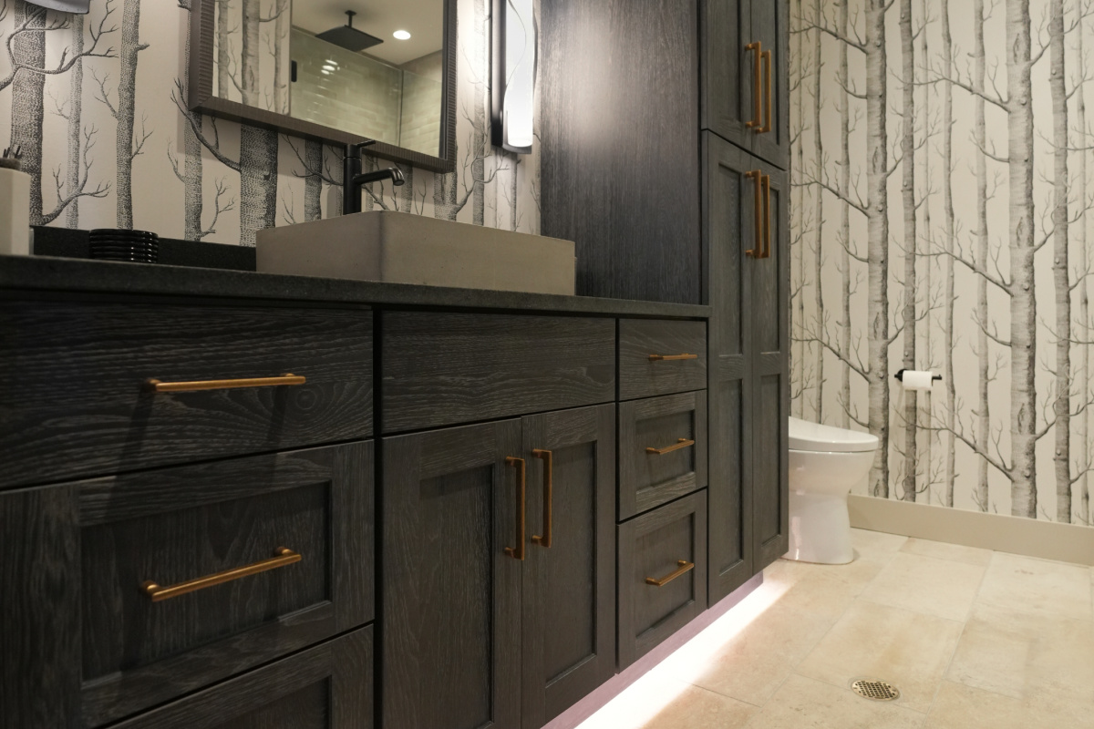 Bathroom vanity cabinets with dark Midnight stain. Bathroom uses "Woods" wall paper.